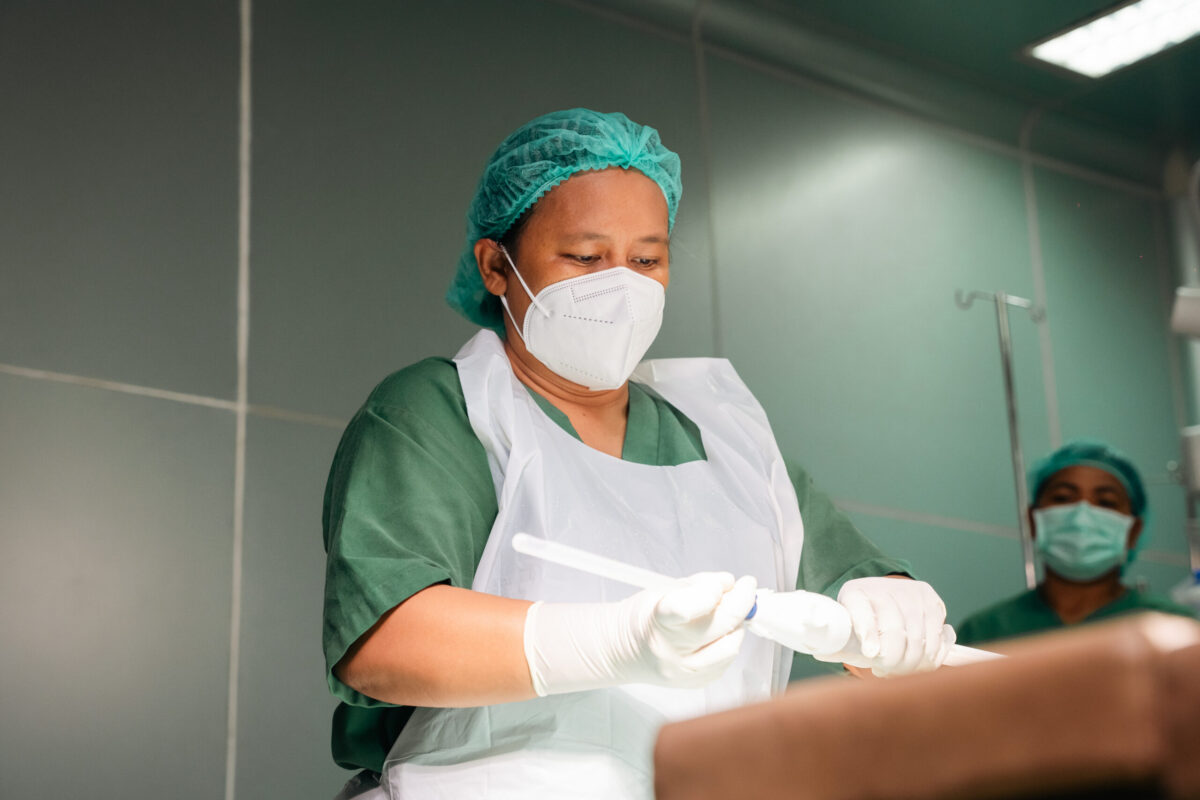 Woman in hospital scrubs and gown.