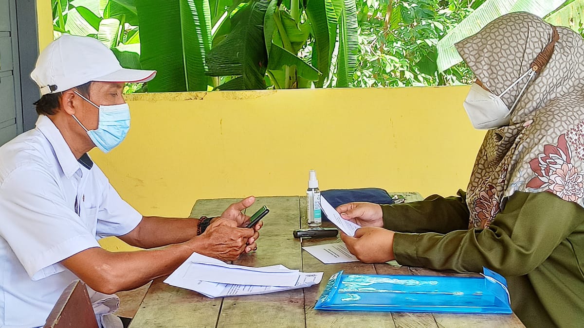 Two people wearing masks meeting at a table.