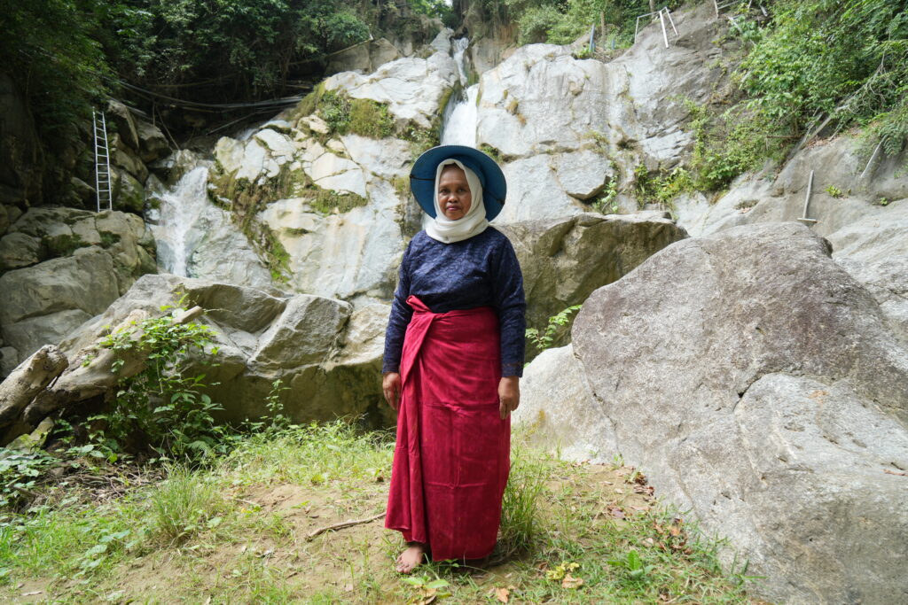 Seorang wanita berdiri di depan bebatuan.