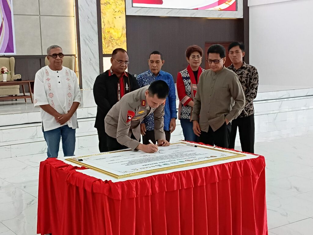 Sekelompok individu menandatangani sebuah dokumen.